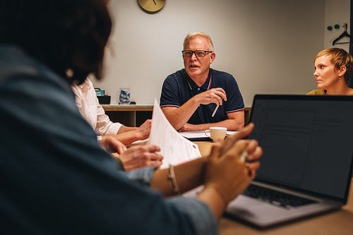 Senior man talking to colleagues in conference meeting
