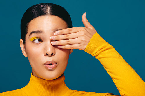 Feeling radiant with eyeshadow, woman stands in a studio with makeup on