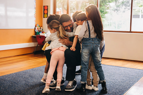 Emotional back to school welcome. Elementary school teacher hugs his students as they return to class