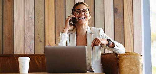 Happy business woman talking on phone in a cafe