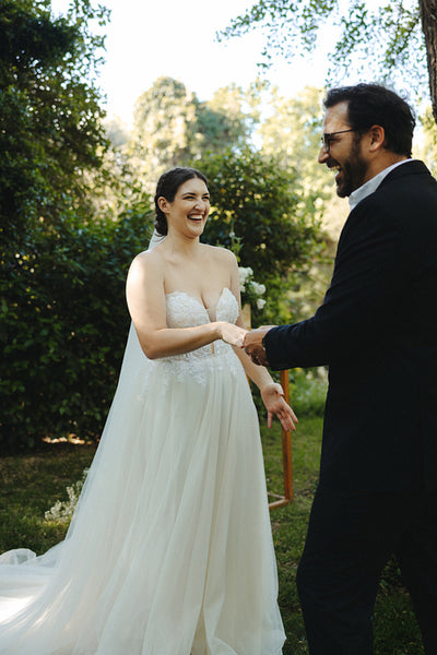 Bride and groom laughing in outdoor garden during wedding day celebration