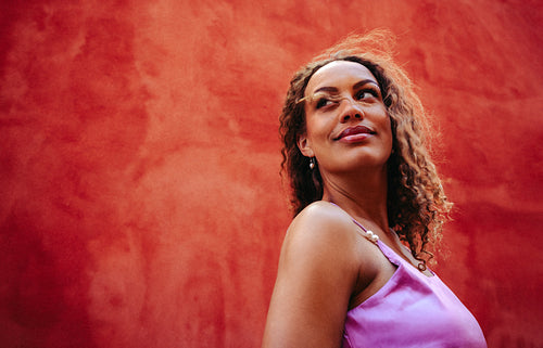 Woman poses outdoors against a red wall in a lifestyle portrait