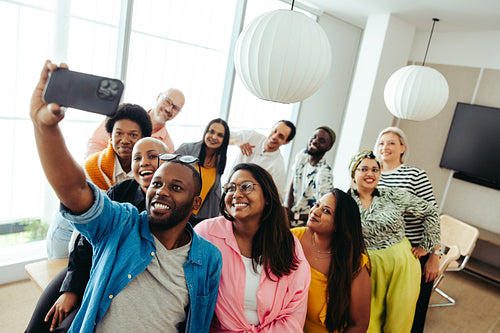 Diverse company group taking a fun selfie in modern office setting