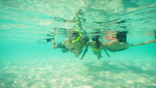 Young family and friends enjoy snorkeling together in the clear tropical ocean water