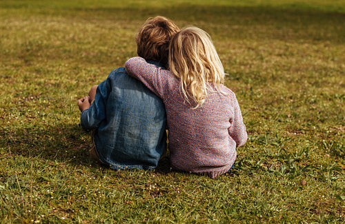 Siblings sitting on the grassy lawn