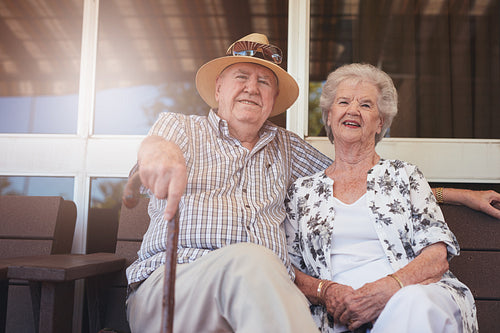 Loving retired couple relaxing on a bench outside their house