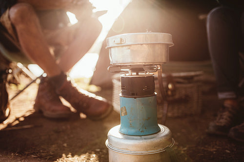 Camp stove with couple sitting in background