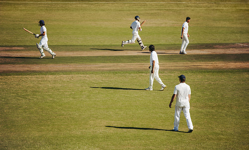 Cricketers in action during an outdoor game on a sunny day
