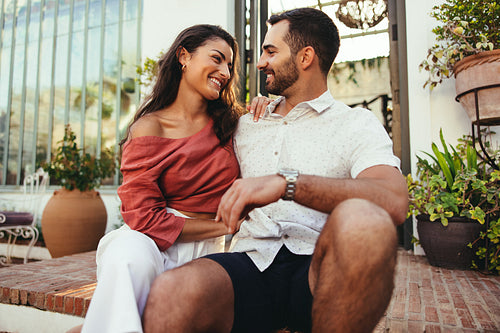 Young couple smiling at each other outside a hotel