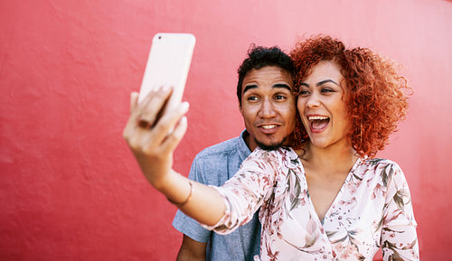 Young couple posing for a selfie using mobile phone.
