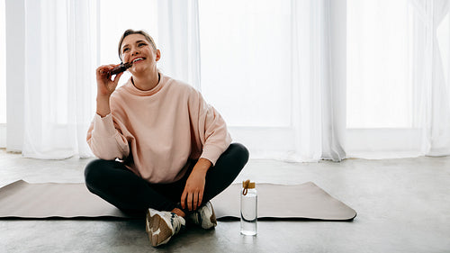 Her protein bar and water support the woman’s post workout recovery on the mat