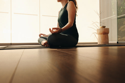 Mature woman practicing sukhasana at home