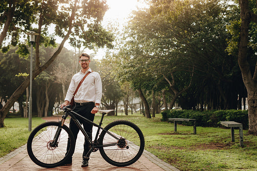 Man standing in park with his bike
