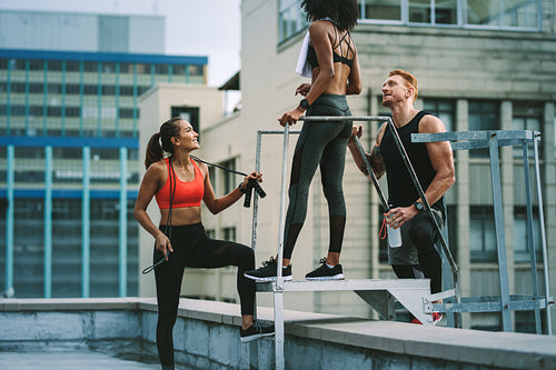 Fitness people relaxing after workout standing on rooftop