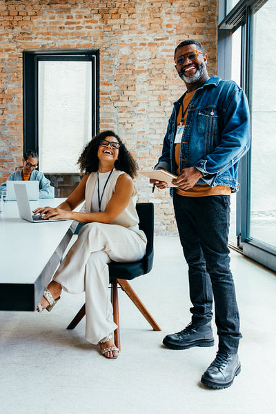Stylish business people working together in a fresh and open office space with creative workspace, laptop, and smiling colleagues