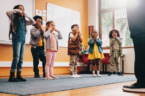 School children moving along to an educational song, kids participating in a class activity with their teacher