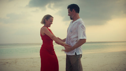 Happy couple enjoying a romantic sunset dance on a beautiful tropical beach