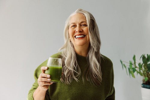Woman enjoys green juice for nutrition at home