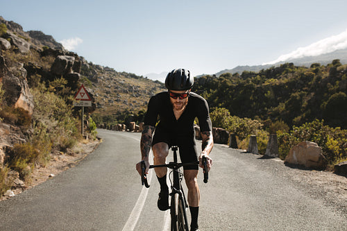 Sportsman climbing up the hill on a road bike