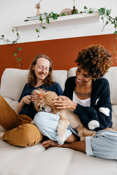 Two friends enjoying time with a small dog at home