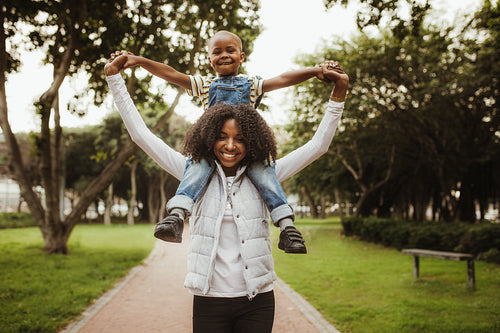 Mother carrying son on shoulders at the park