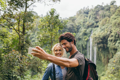 Couple taking picture in front of waterfall