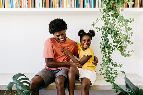 Afro family bonding at home: Siblings laughing and having fun together in living room