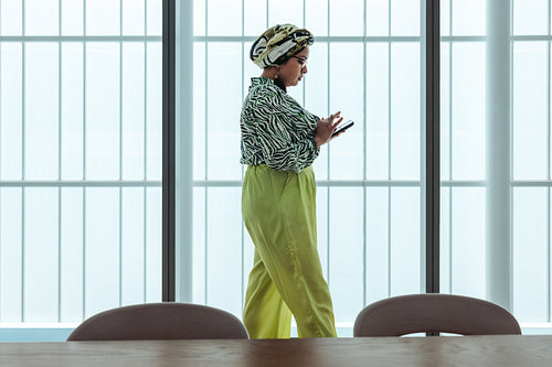 Indian businesswoman wearing vibrant attire uses a smartphone in a modern office setting