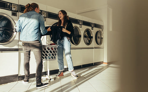 Happy couple washing clothes together in a laundry room
