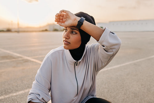 Muslim sportswoman wiping her sweat outdoors