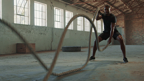 Strong man working out with battle ropes in gym