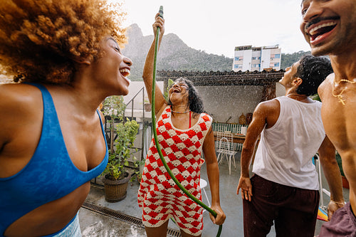 Group of friends dancing and laughing under summer water spray