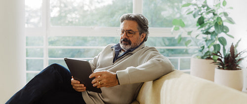Senior man explores online services on a tablet at home