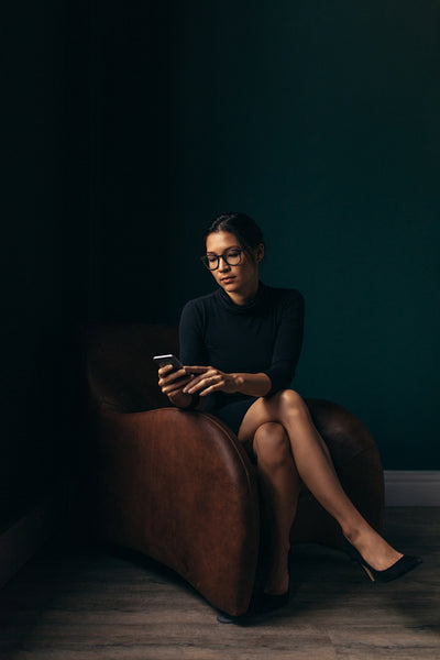 Sophisticated woman on chair using mobile phone