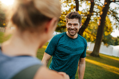 Fit young man smiling with woman in park