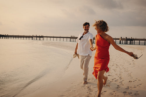 Vitality in paradise: Retired couple laughing and running on a beautiful beach