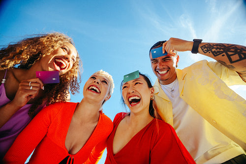 Students enjoying vacation while laughing with credit cards outdoors