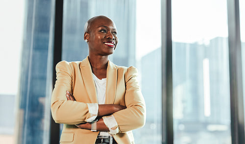 Confident black businesswoman standing by window in office