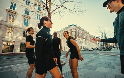 Laughing after exercise, the running friends gather on an urban street