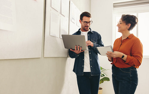 Two happy business colleagues having a discussion in an office