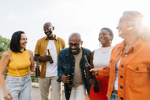 Diverse team of colleagues enjoying drinks and bonding outdoors with laughter