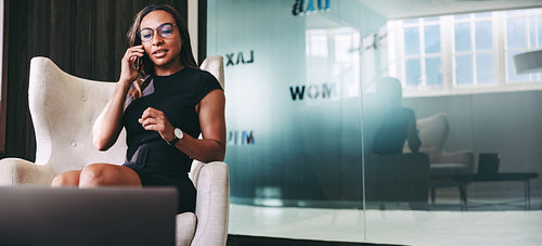 Confident young businesswoman taking a phone call in her office