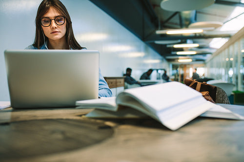 Female student studying with laptop at university campus