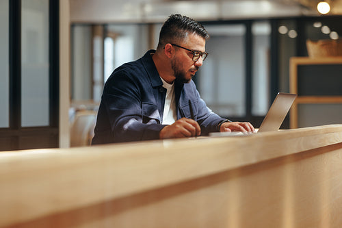 Graphic designer working on a laptop in a coworking office