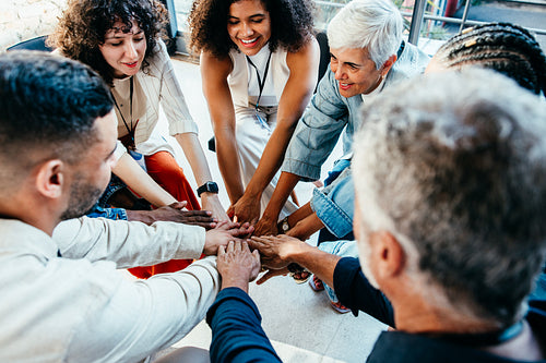 Diverse team of coworkers putting their hands together, showing unity and teamwork