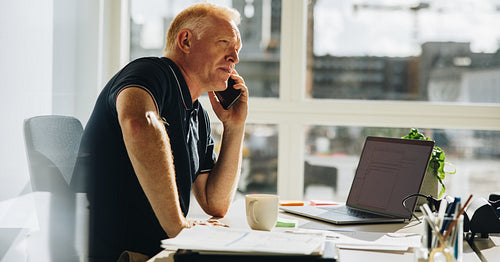 Businessman talking over mobile phone at work