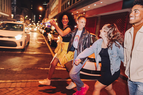 Group of friends crossing a road together at night