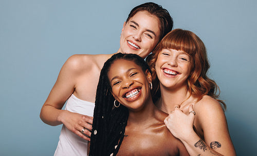 Cheerful women with different skin tones smiling at the camera in a studio