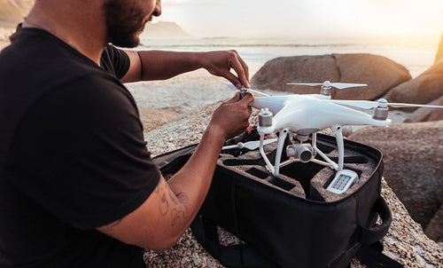 Man sitting at rocky beach with a drone