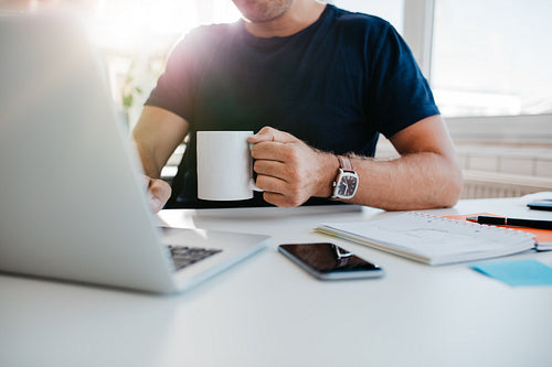 Businessman with cup of coffee working on laptop